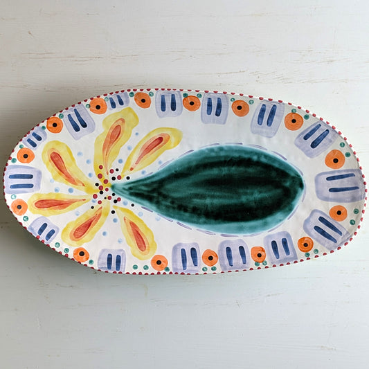 Multicoloured white ceramic platter with bottle tree pattern on a white background