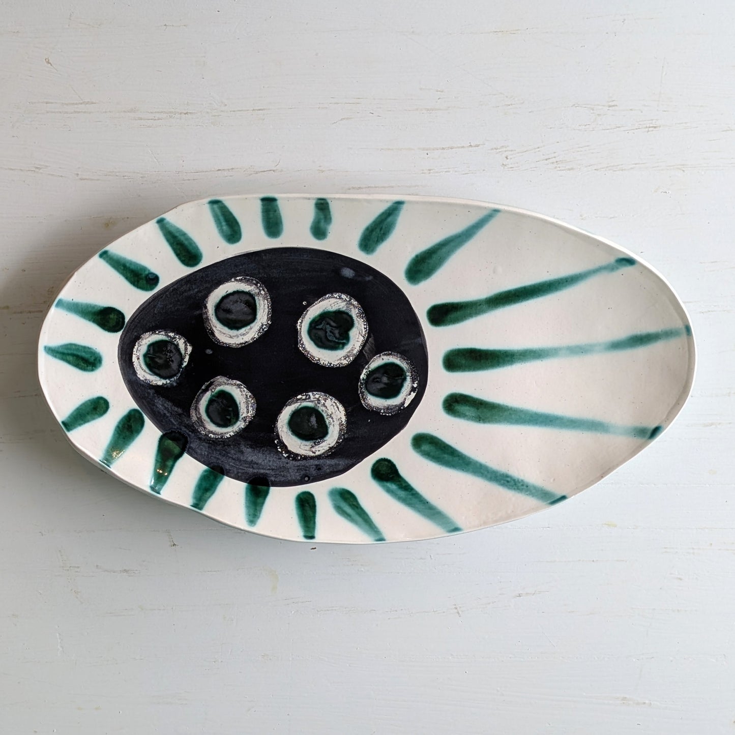 White ceramic platter with dark green centre and green accents on a white background
