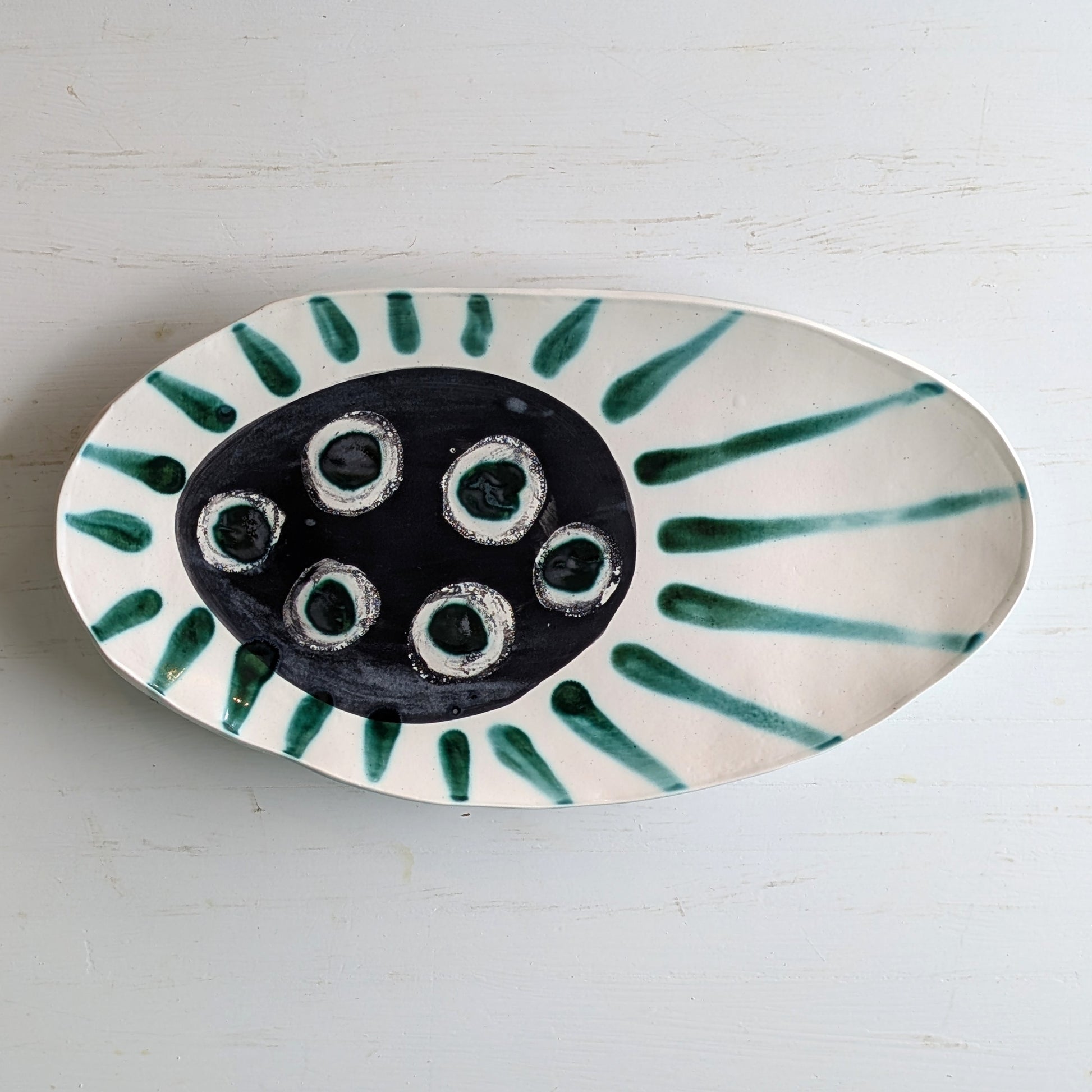 White ceramic platter with dark green centre and green accents on a white background