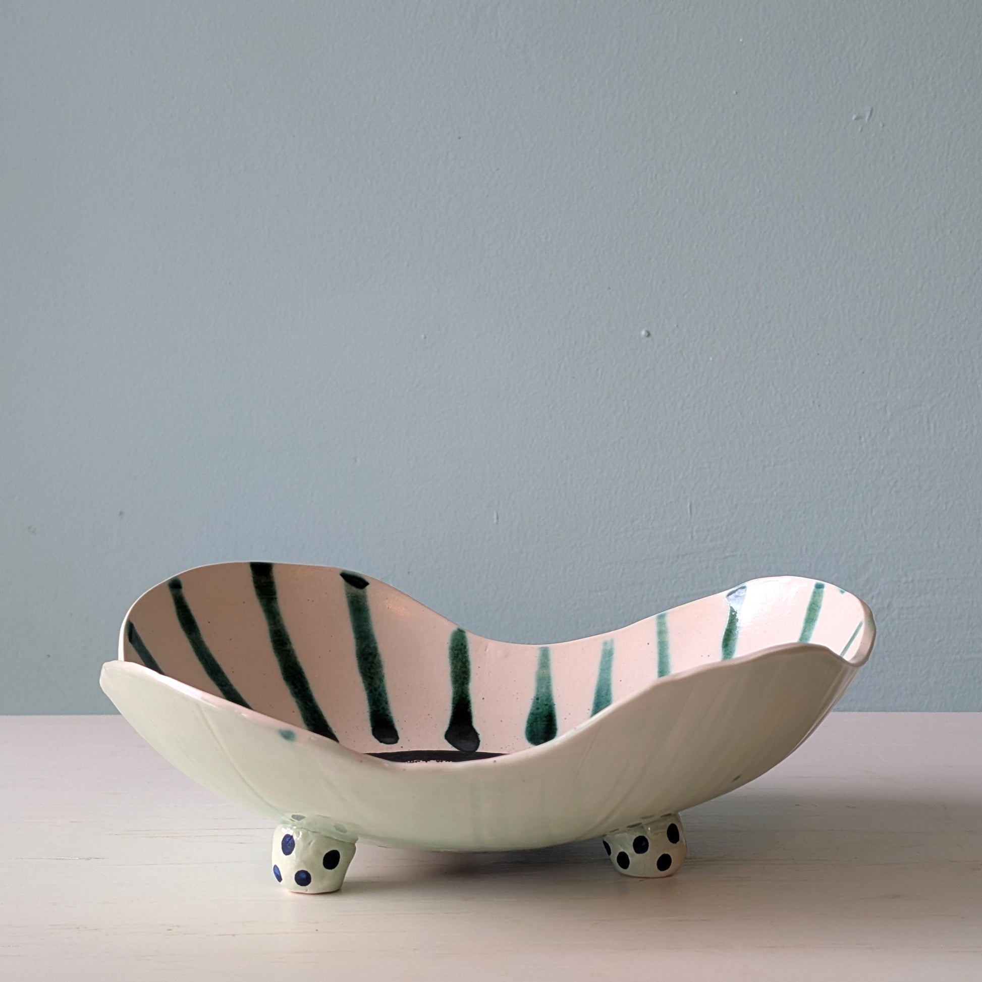 Ceramic bowl with wavy design and green stripes on a light blue background