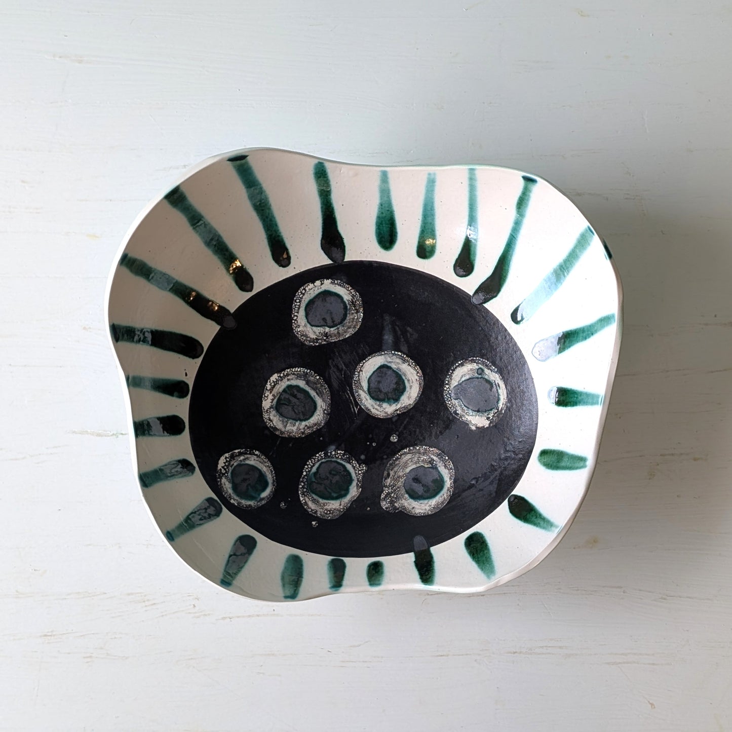 Ceramic bowl with dark green centre and green accents on a white background