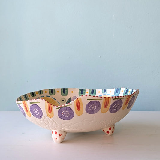 Decorative ceramic bowl with colorful patterns on a light blue background