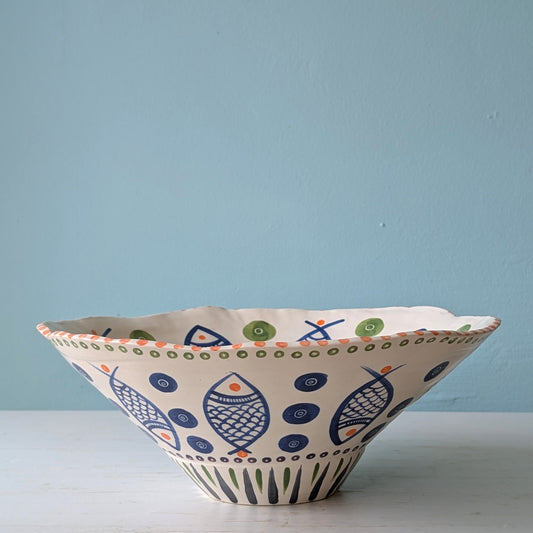 Decorative ceramic bowl with fish pattern on a light blue background