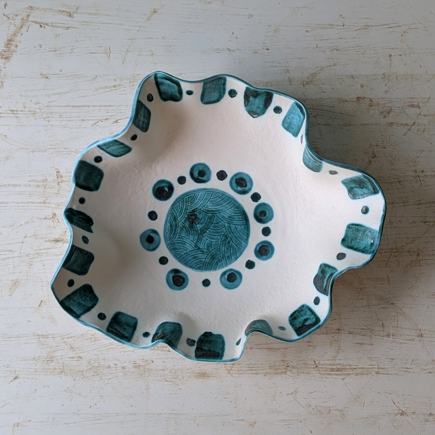 Ceramic bowl with green patterns on a wooden surface