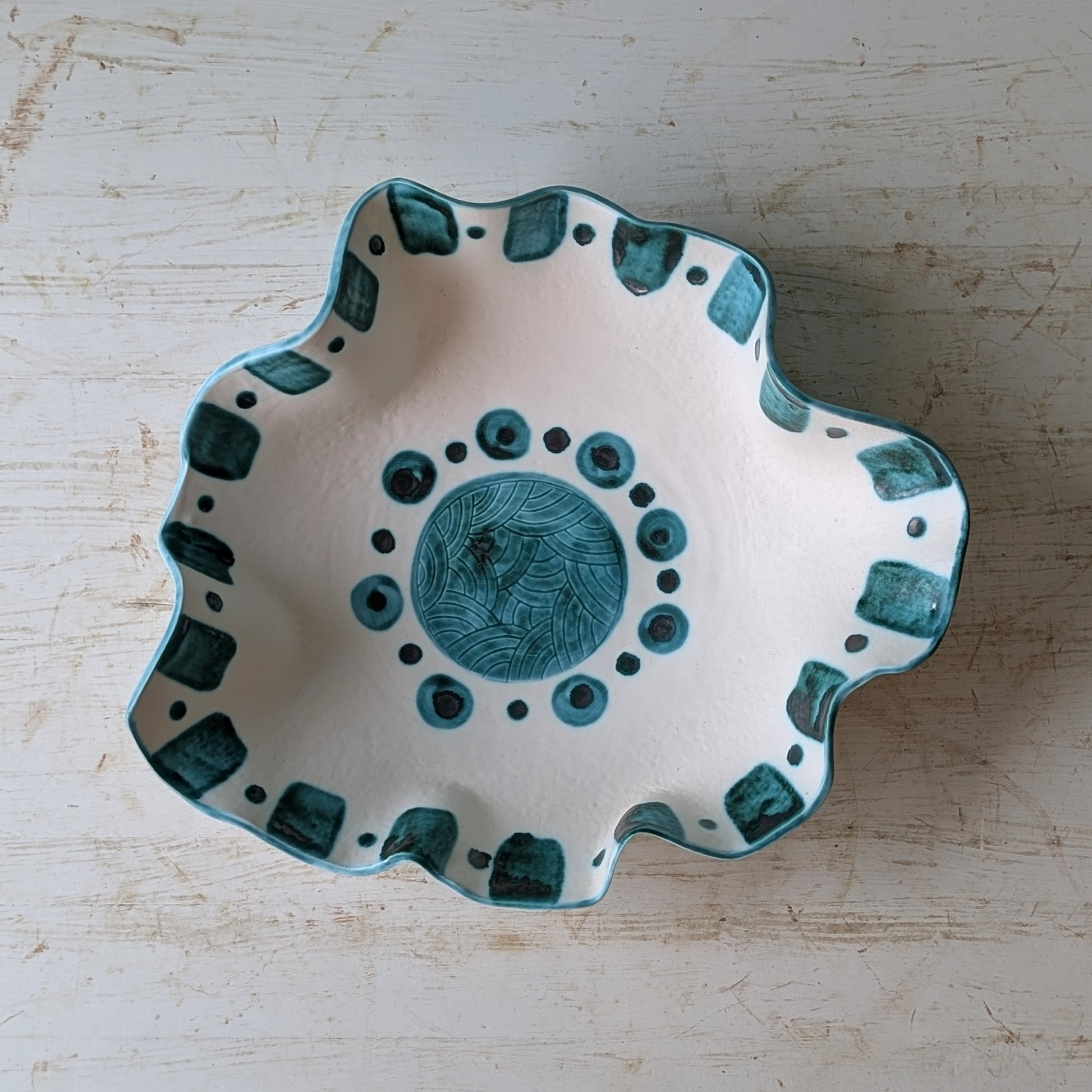 Ceramic bowl with green patterns on a wooden surface
