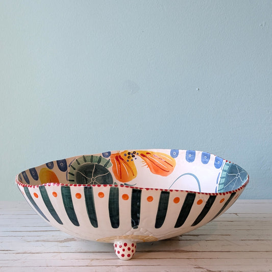 Front view of a white ceramic bowl with green, blue and orange abstract floral pattern