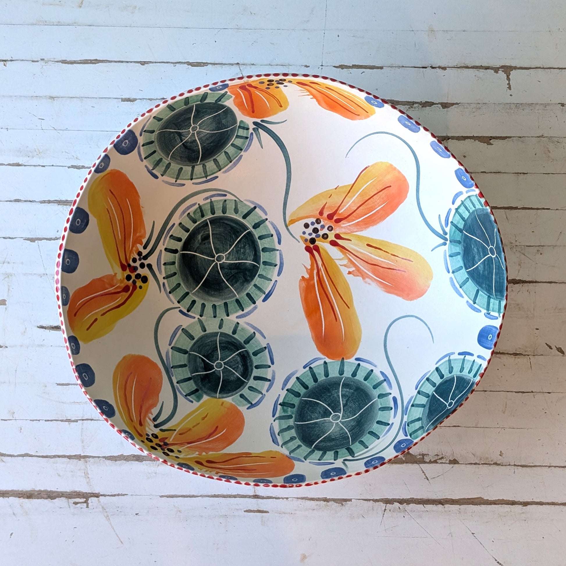 Top view of a white ceramic bowl with blue, green and orange abstract floral pattern