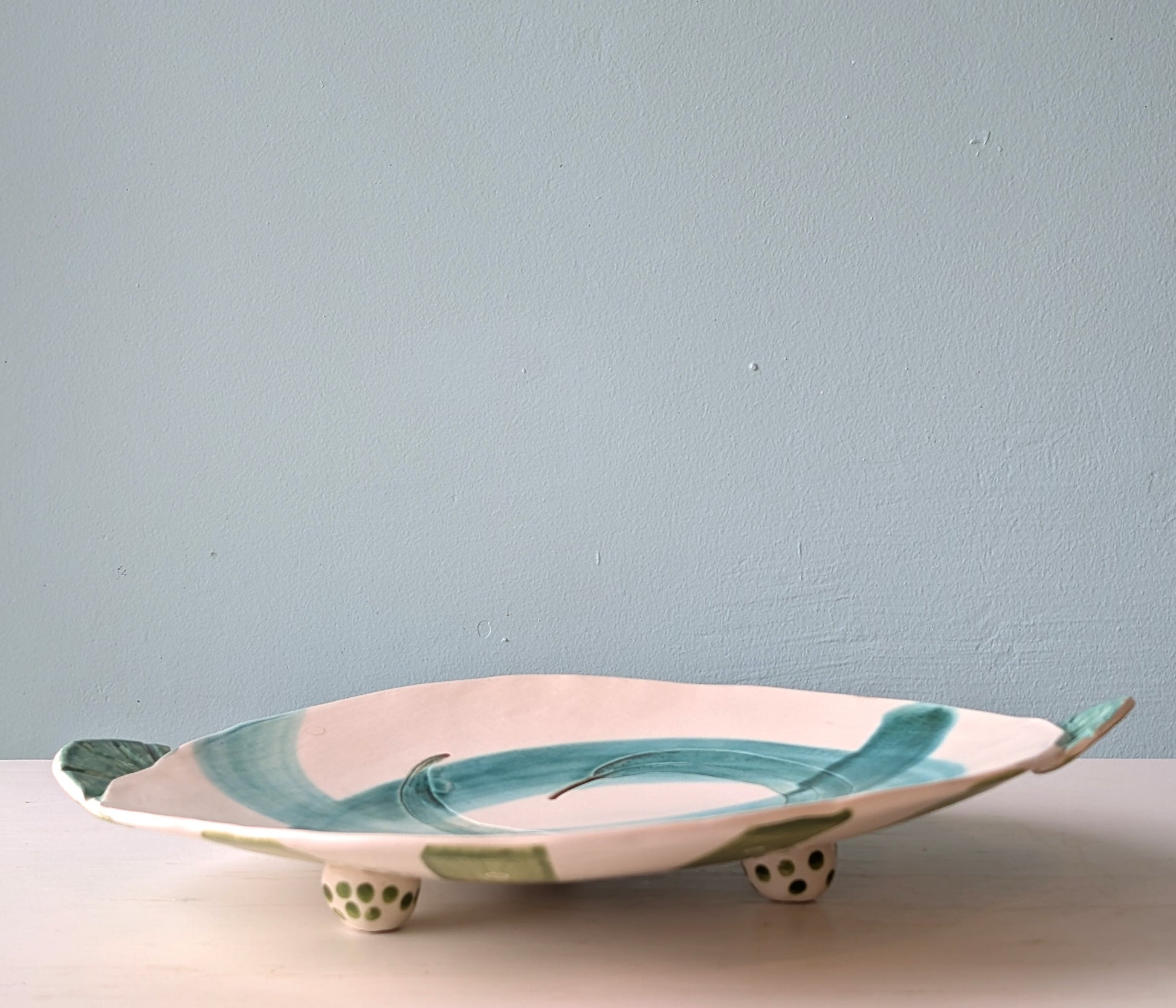 Ceramic dish with green and white design on a blue background