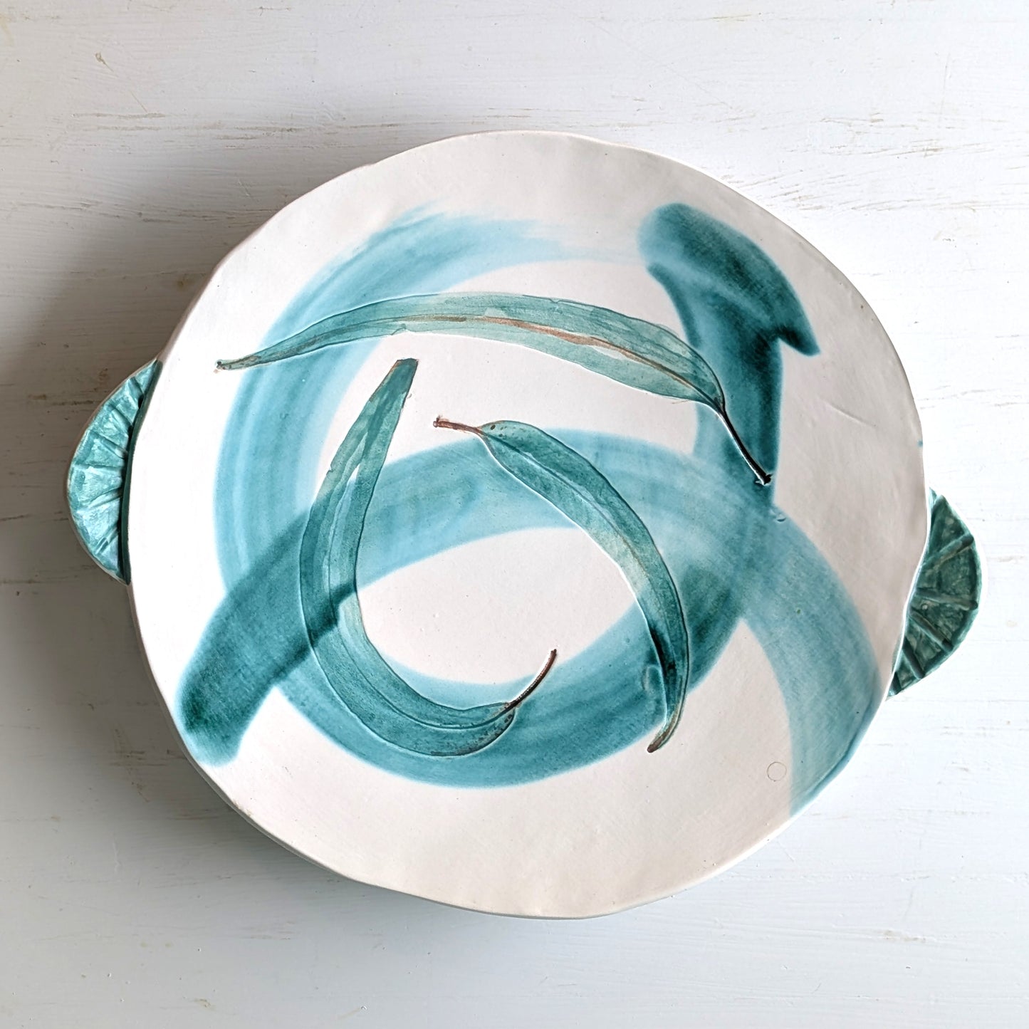 Ceramic plate with green leaf design on a white background