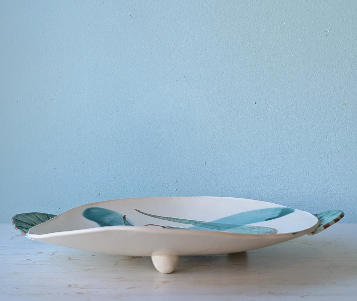 Ceramic bowl with green leaf design on a light blue background