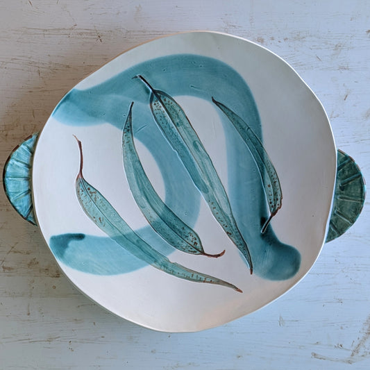 White and green ceramic platter with leaf pattern on a white table