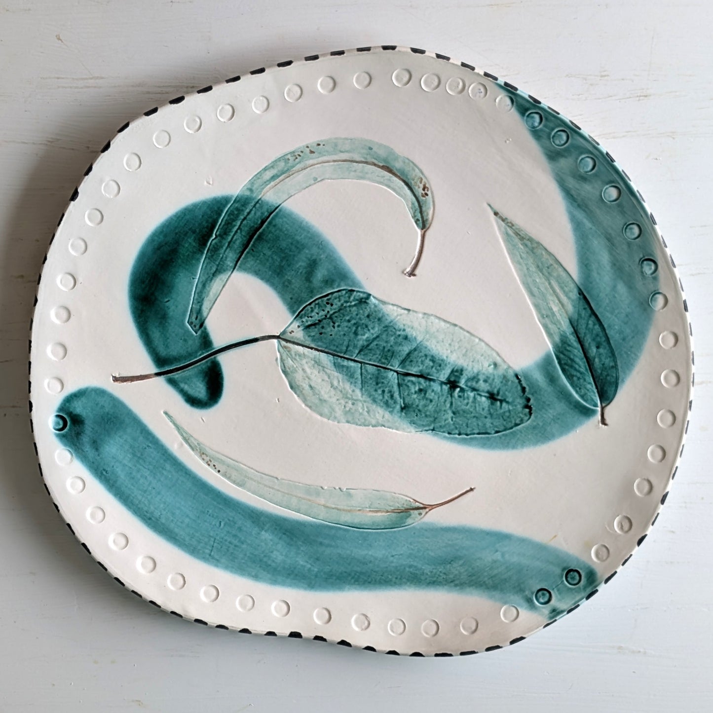 Ceramic plate with green leaf design on a white background