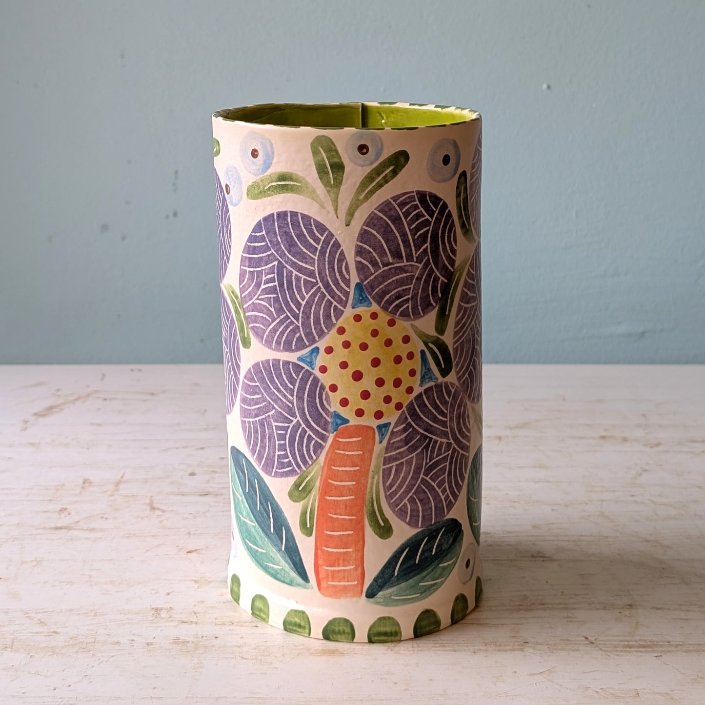 Decorative vase with floral pattern on a wooden surface and light blue background