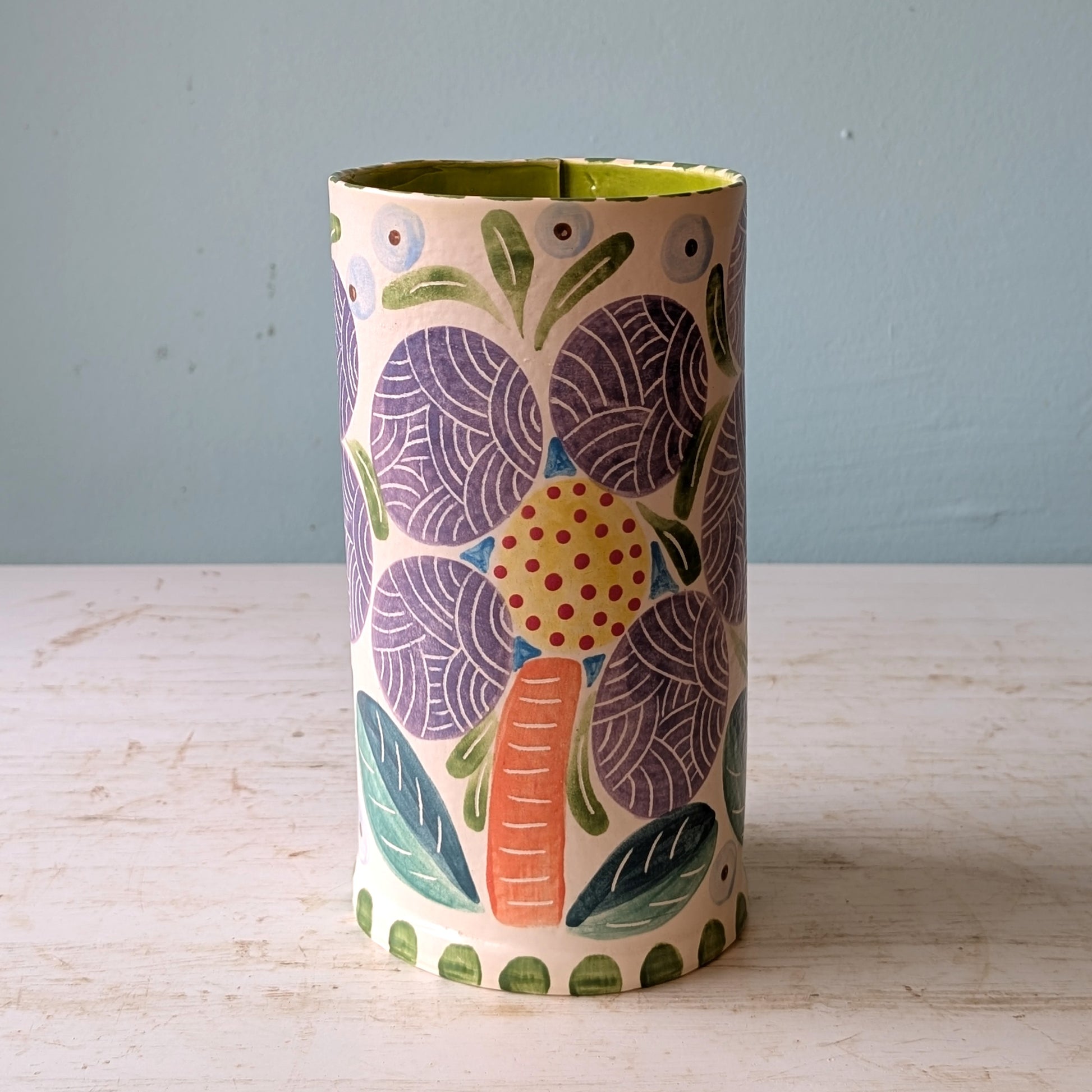 Decorative vase with floral pattern on a wooden surface and light blue background
