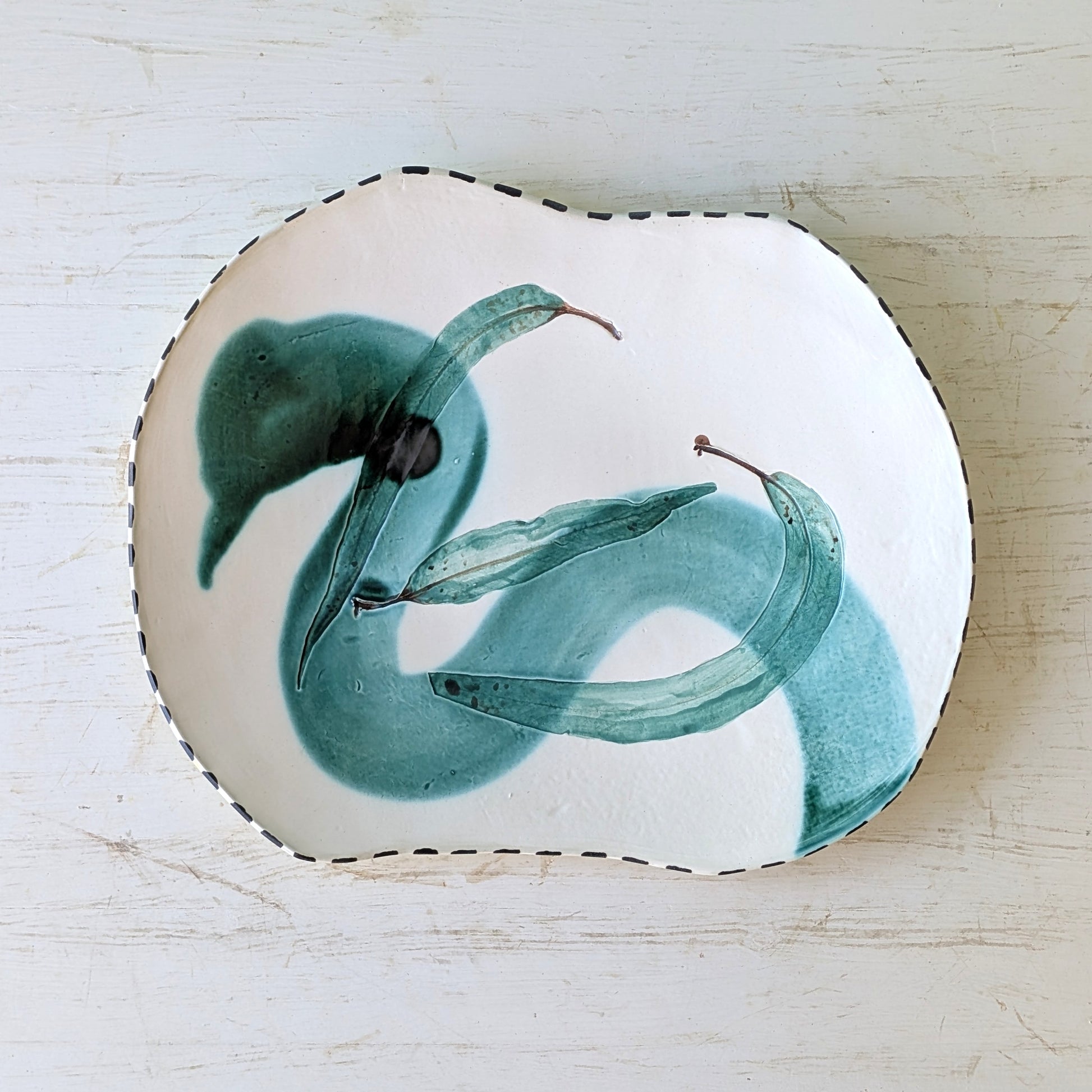 Freeform ceramic platter with green abstract pattern on white table