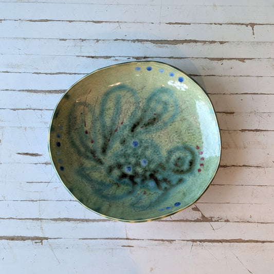 Top view of a ceramic bowl with blue and green abstract fish pattern