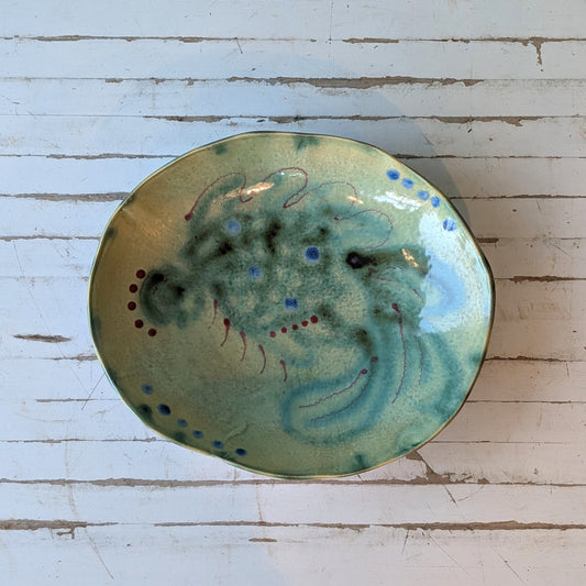 Top view of a ceramic bowl with green and blue abstract fish pattern