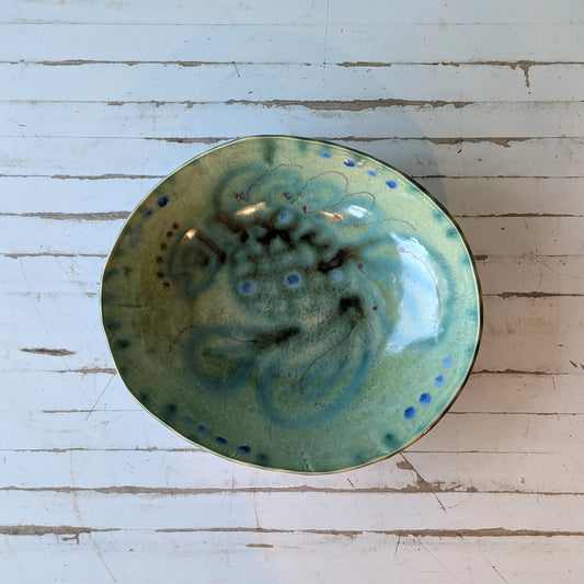 Top view of a ceramic bowl with blue and green abstract fish pattern