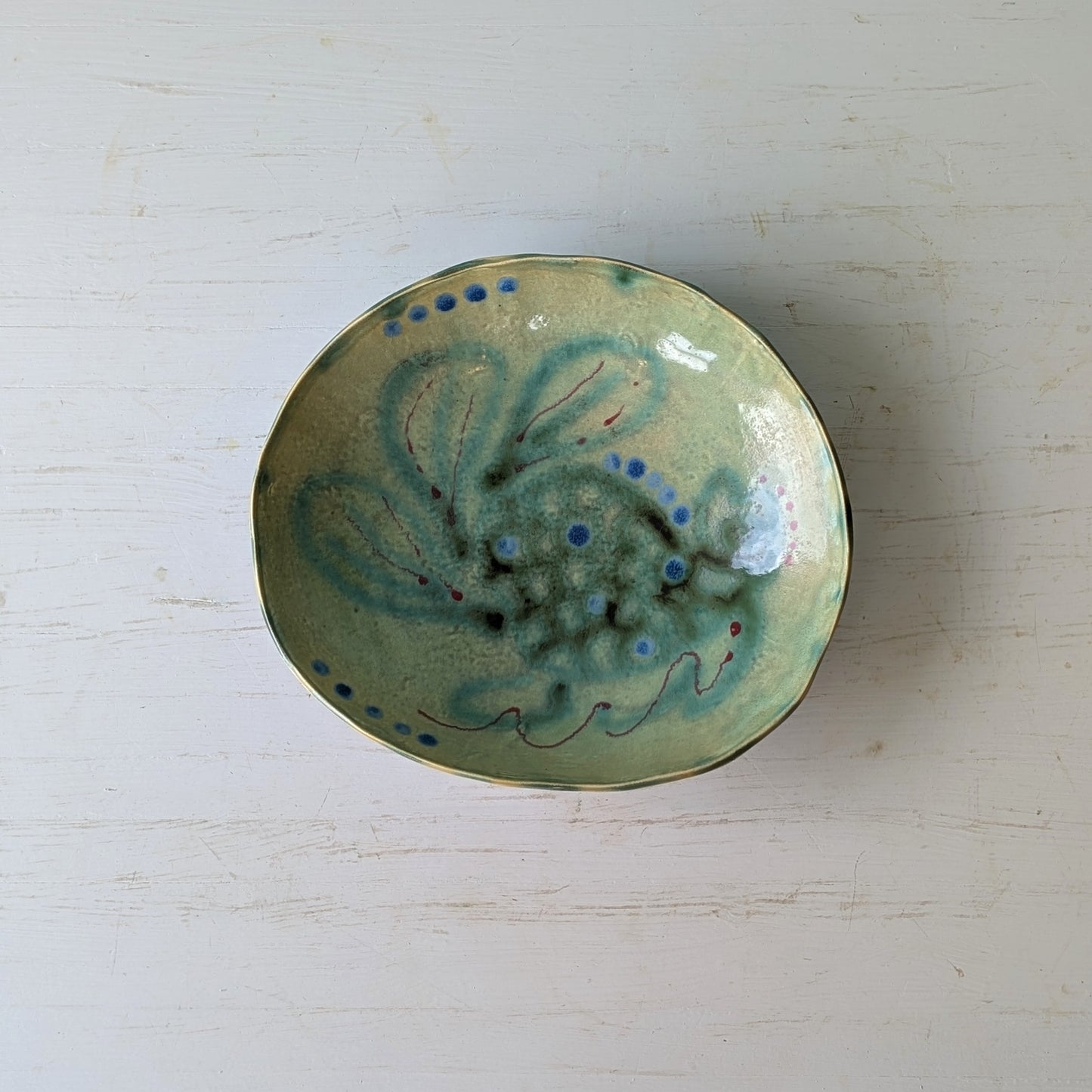 Ceramic bowl with green and blue design on a white surface
