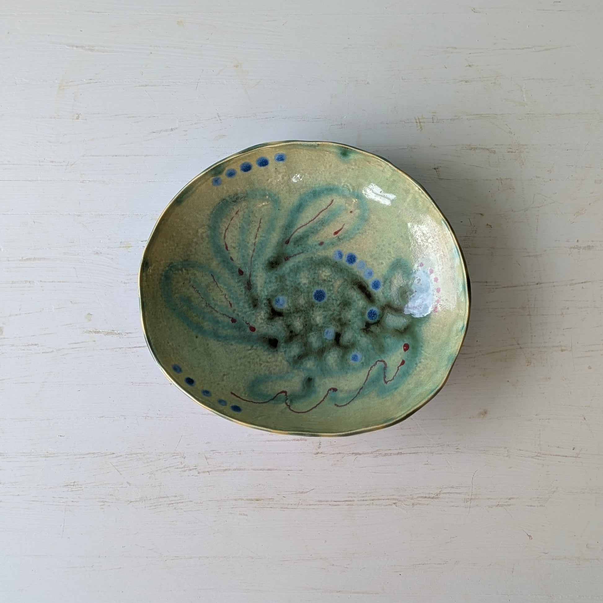 Ceramic bowl with green and blue design on a white surface