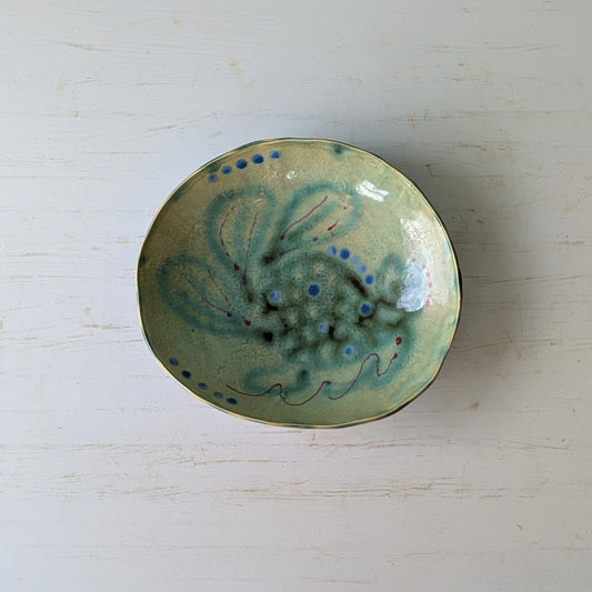 Ceramic bowl with green and blue design on a white surface