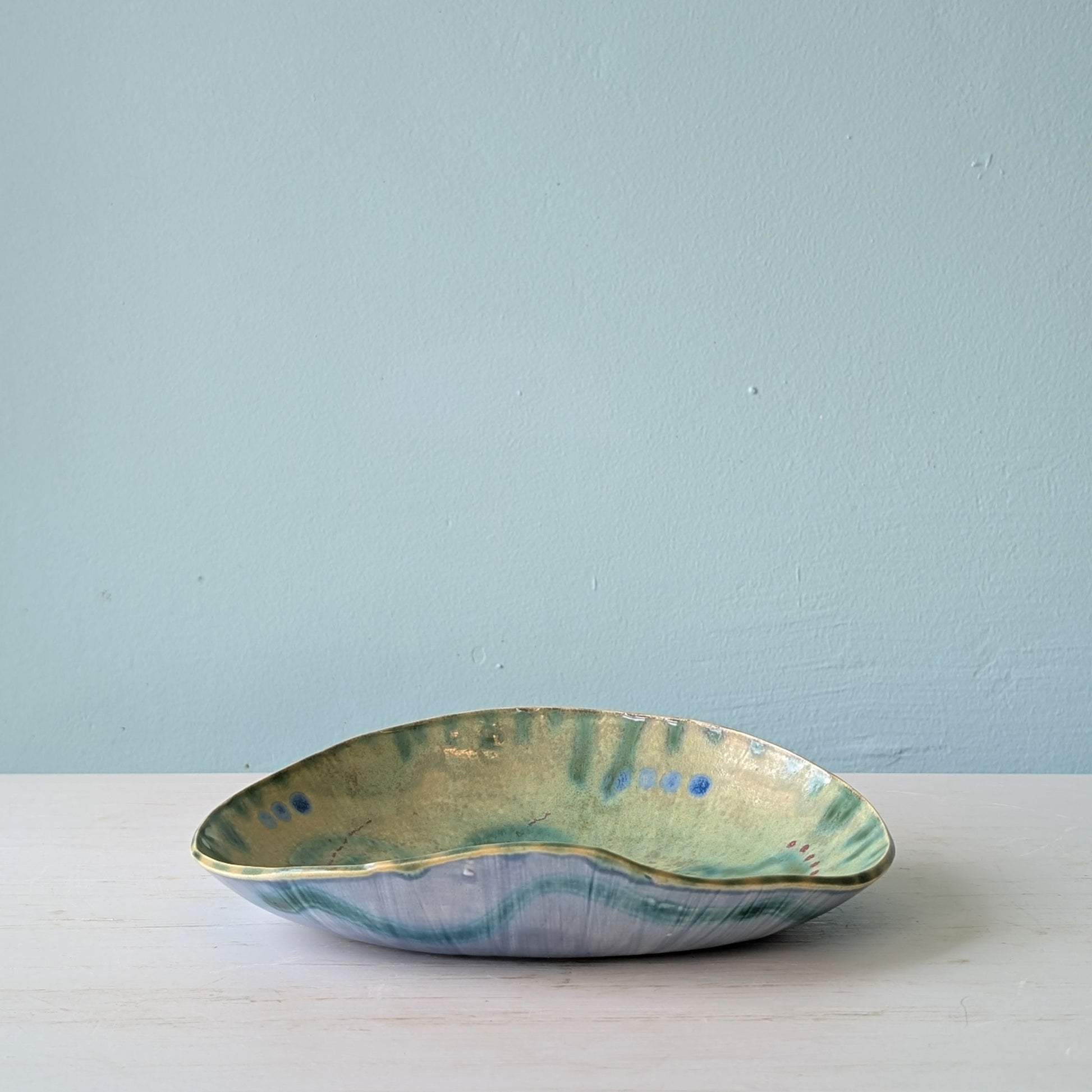 Ceramic bowl with green and blue glaze on a light blue background