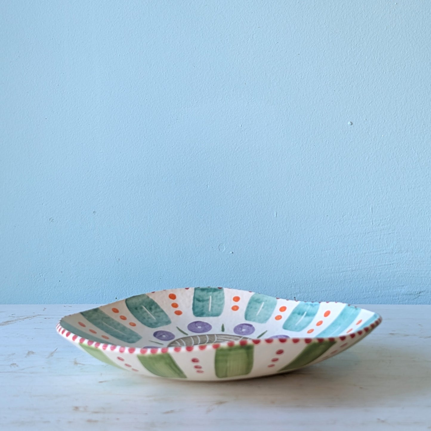 Decorative ceramic bowl with colorful patterns on a light blue background