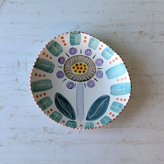Ceramic bowl with floral design on a light blue wooden surface