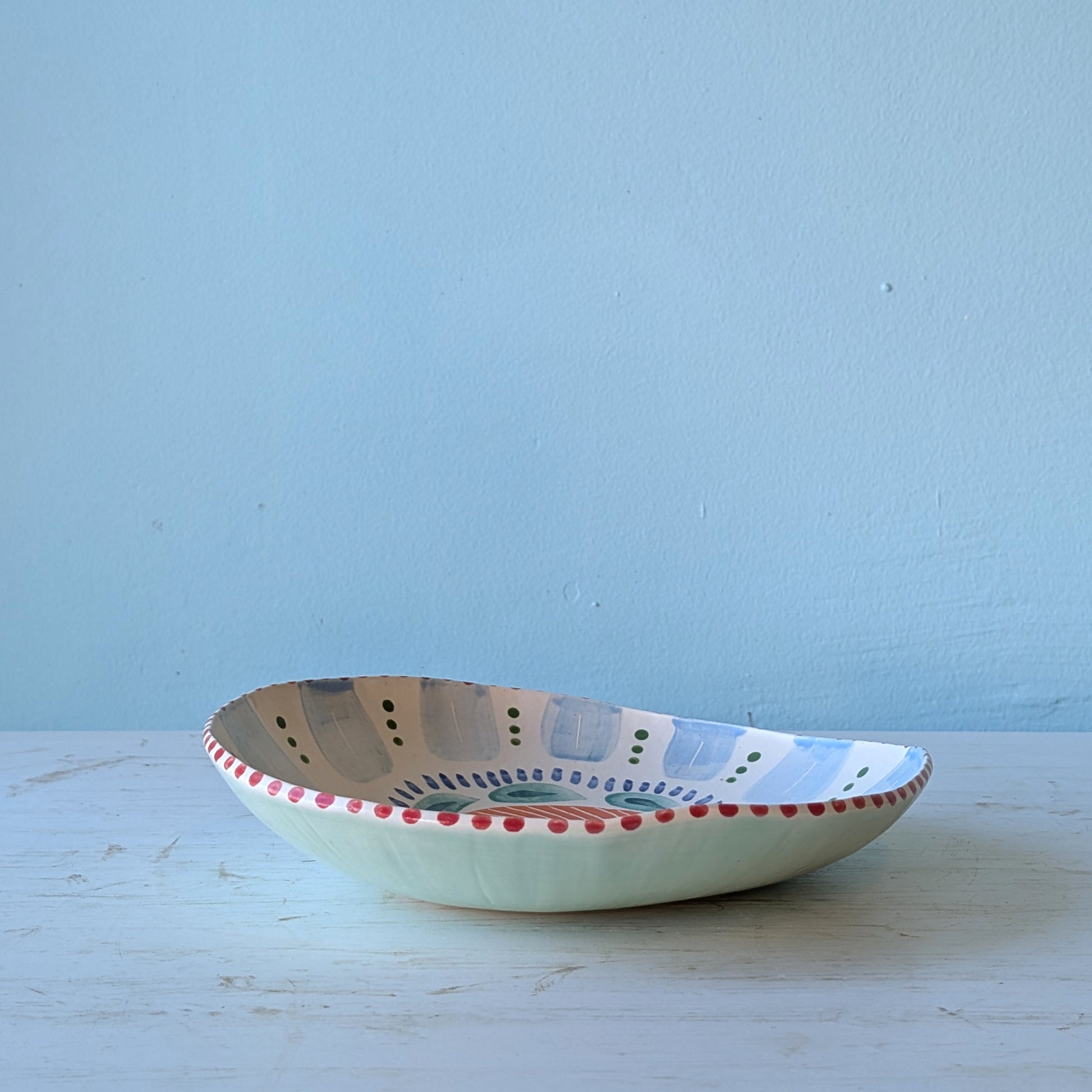 Colourful ceramic bowl with abstract design against a blue wall
