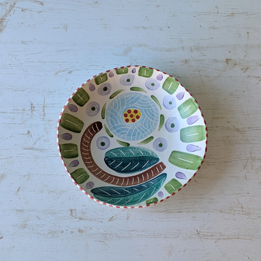 Decorative ceramic bowl with floral design on a light blue wooden surface