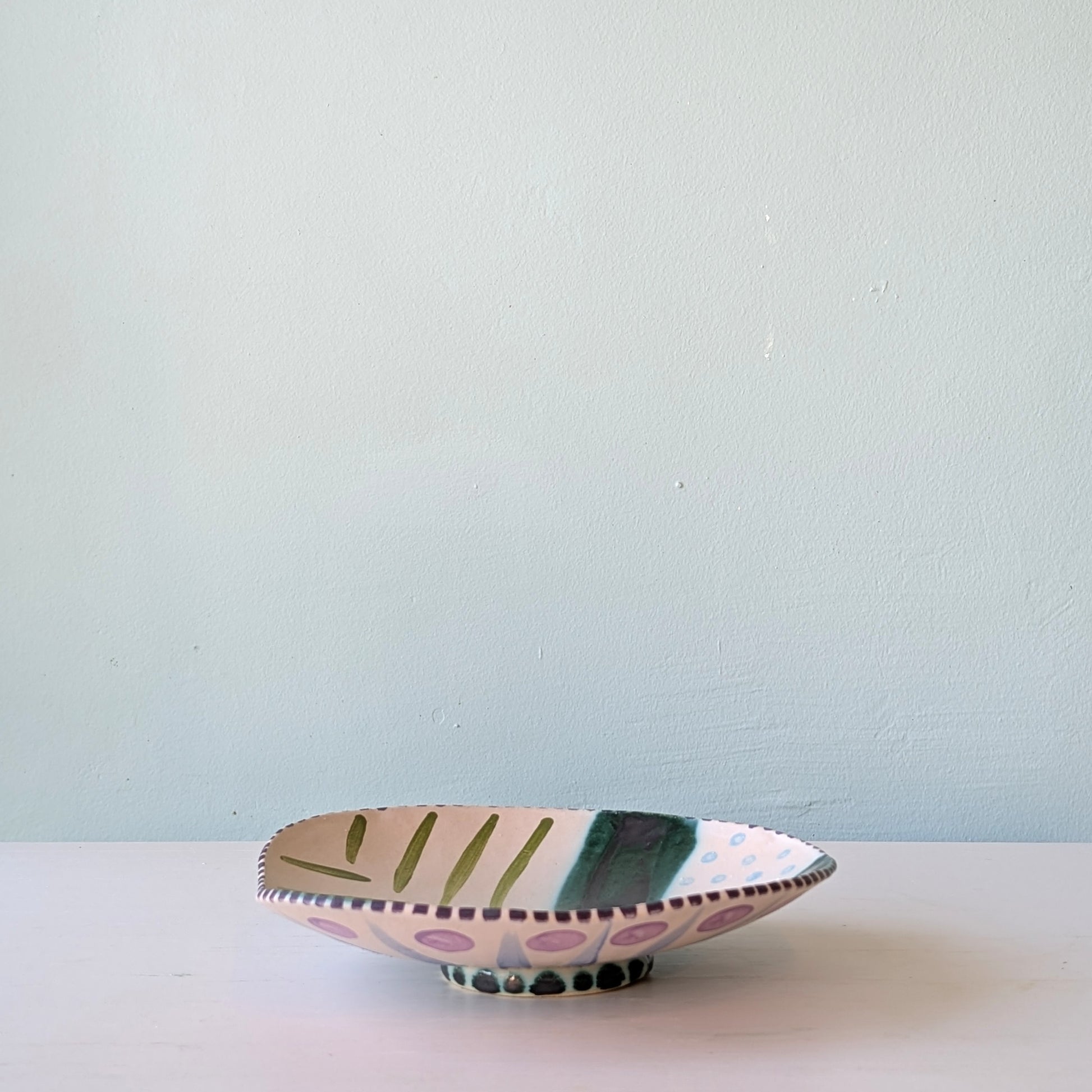 Decorative ceramic bowl with colorful design on a light blue background