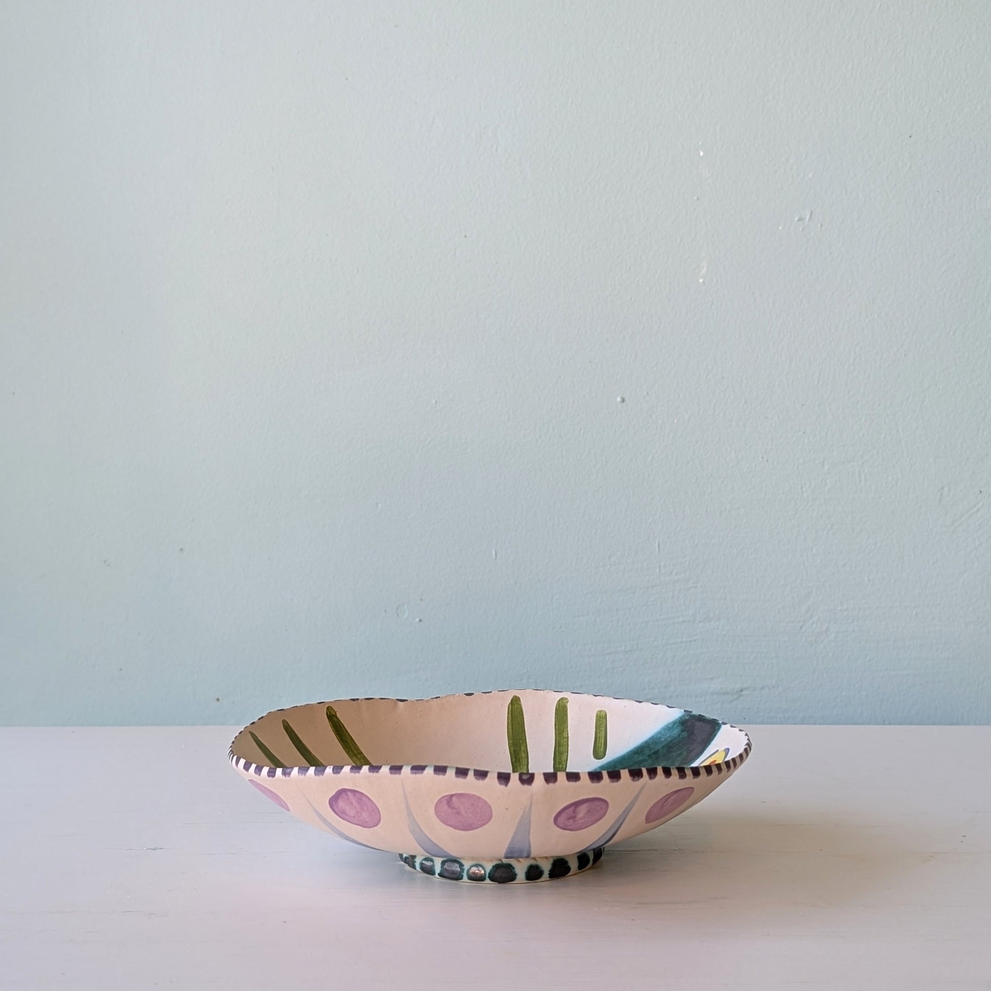 Decorative ceramic bowl with polka dot pattern on a light blue background
