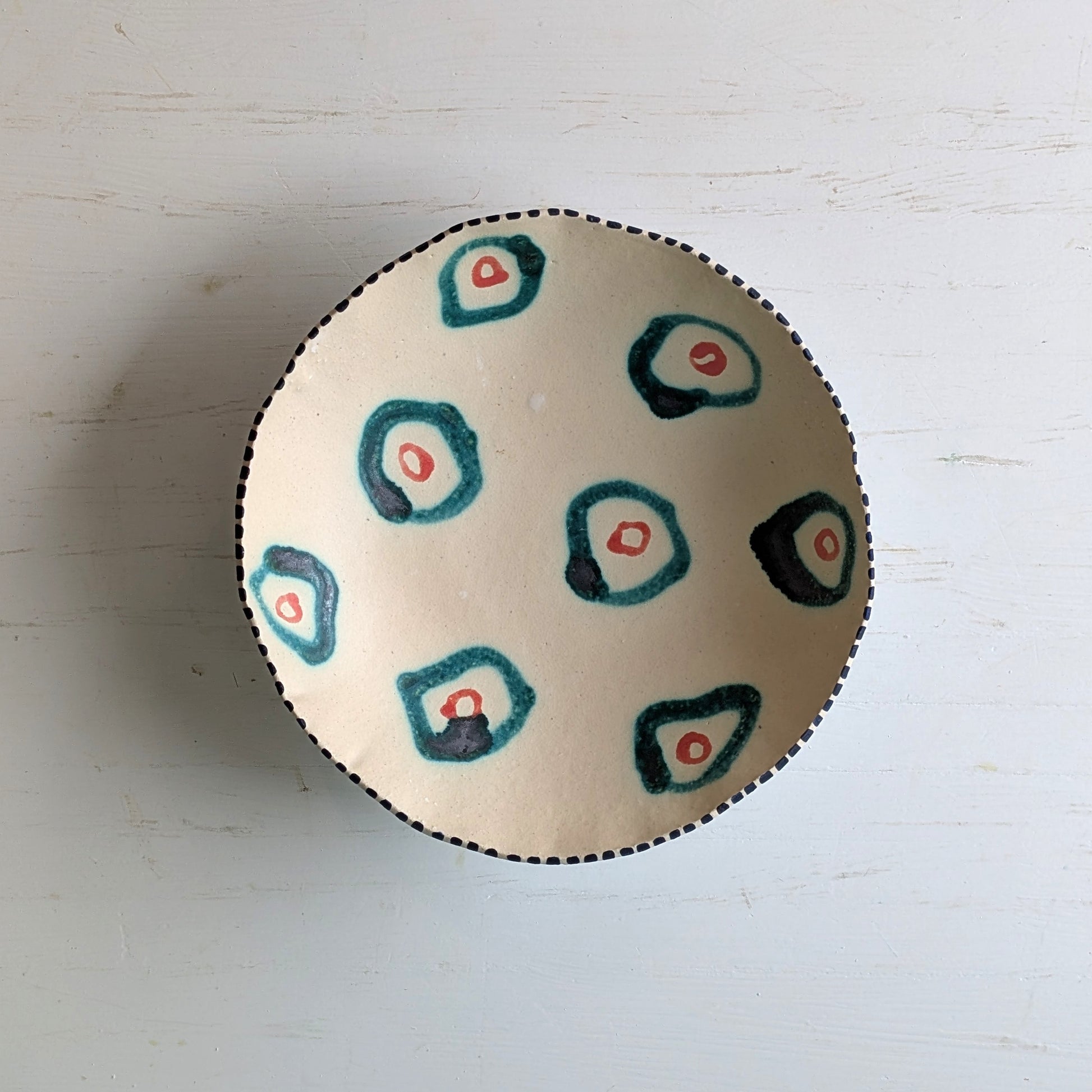 Round ceramic bowl with green abstract design on a white surface