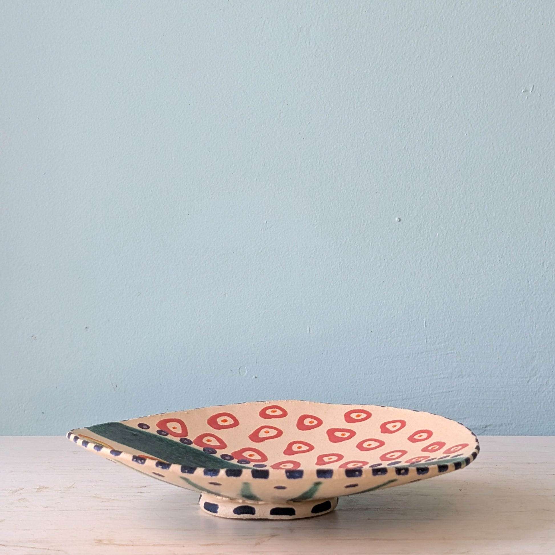 Ceramic plate with red and green pattern on a light blue background