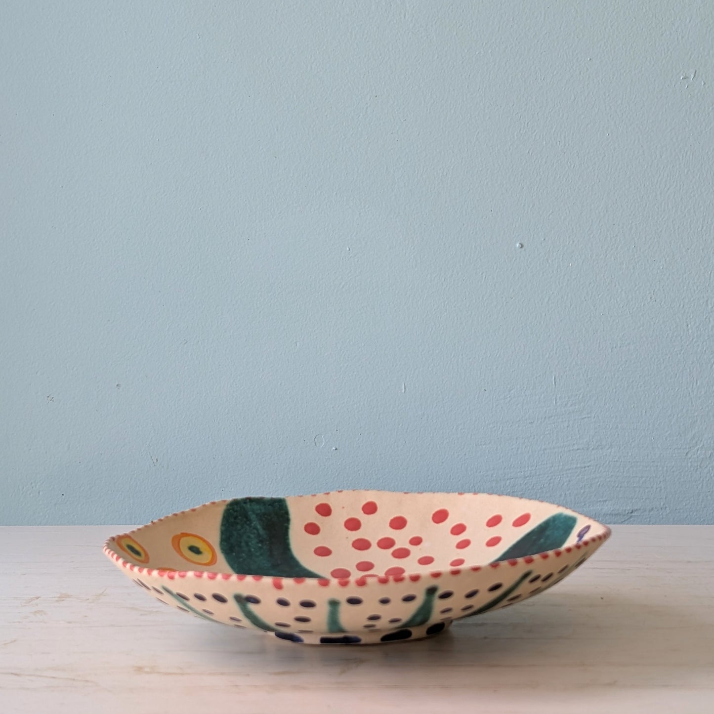 Decorative ceramic bowl with polka dot pattern on a light blue background