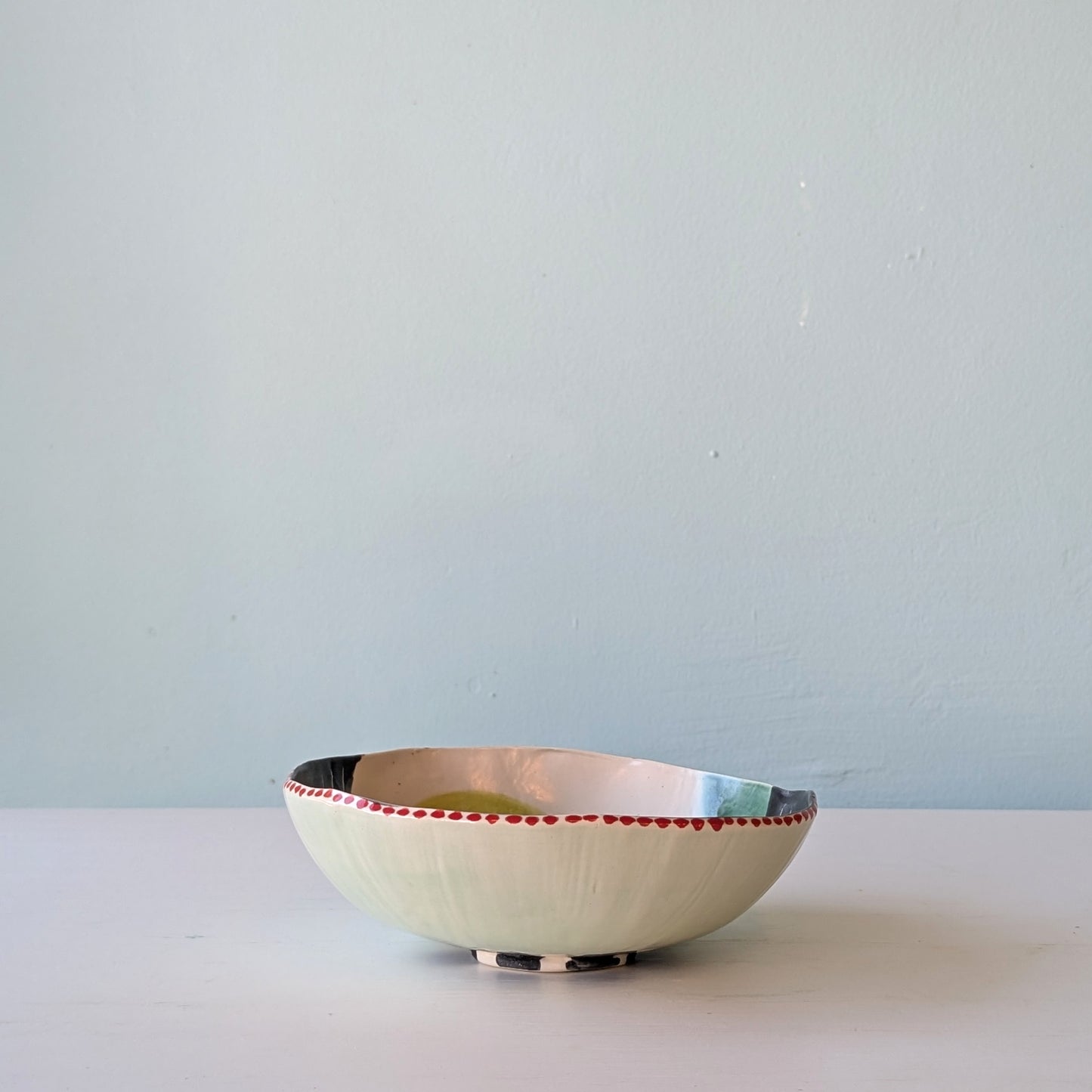 Ceramic bowl with red accents on a white surface and light blue wall background