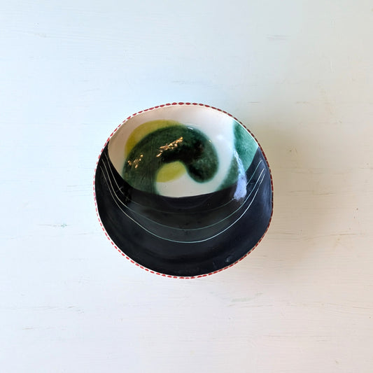 Ceramic bowl with green and white design on a light wooden surface