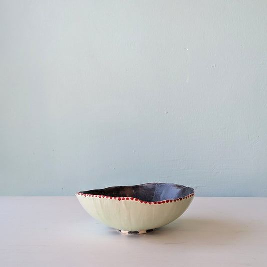 Ceramic bowl with red rim on a white surface and light blue wall background