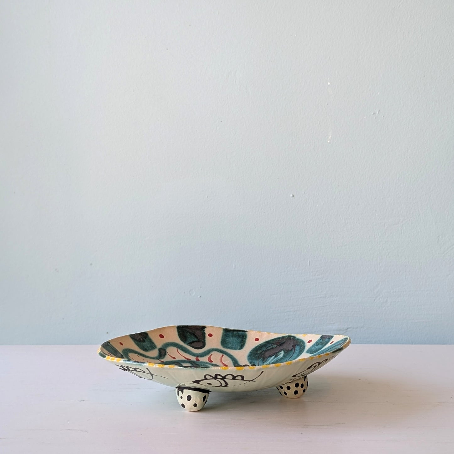 Ceramic dish with fish design on a white surface and light blue background