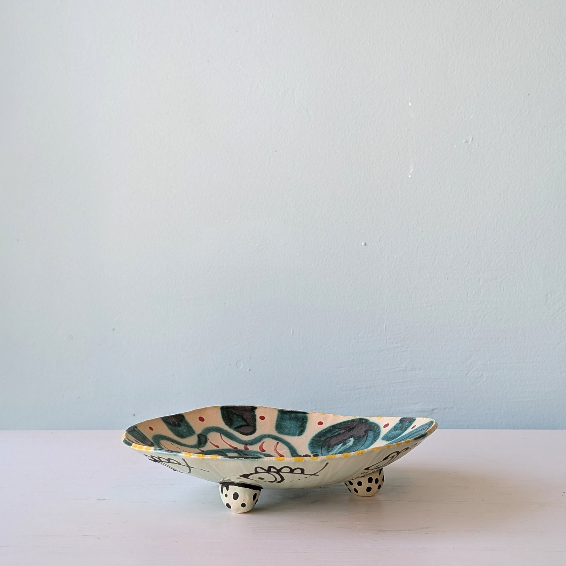 Ceramic dish with fish design on a white surface and light blue background