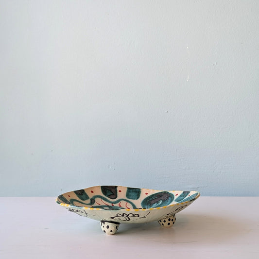 Ceramic dish with fish design on a white surface and light blue background