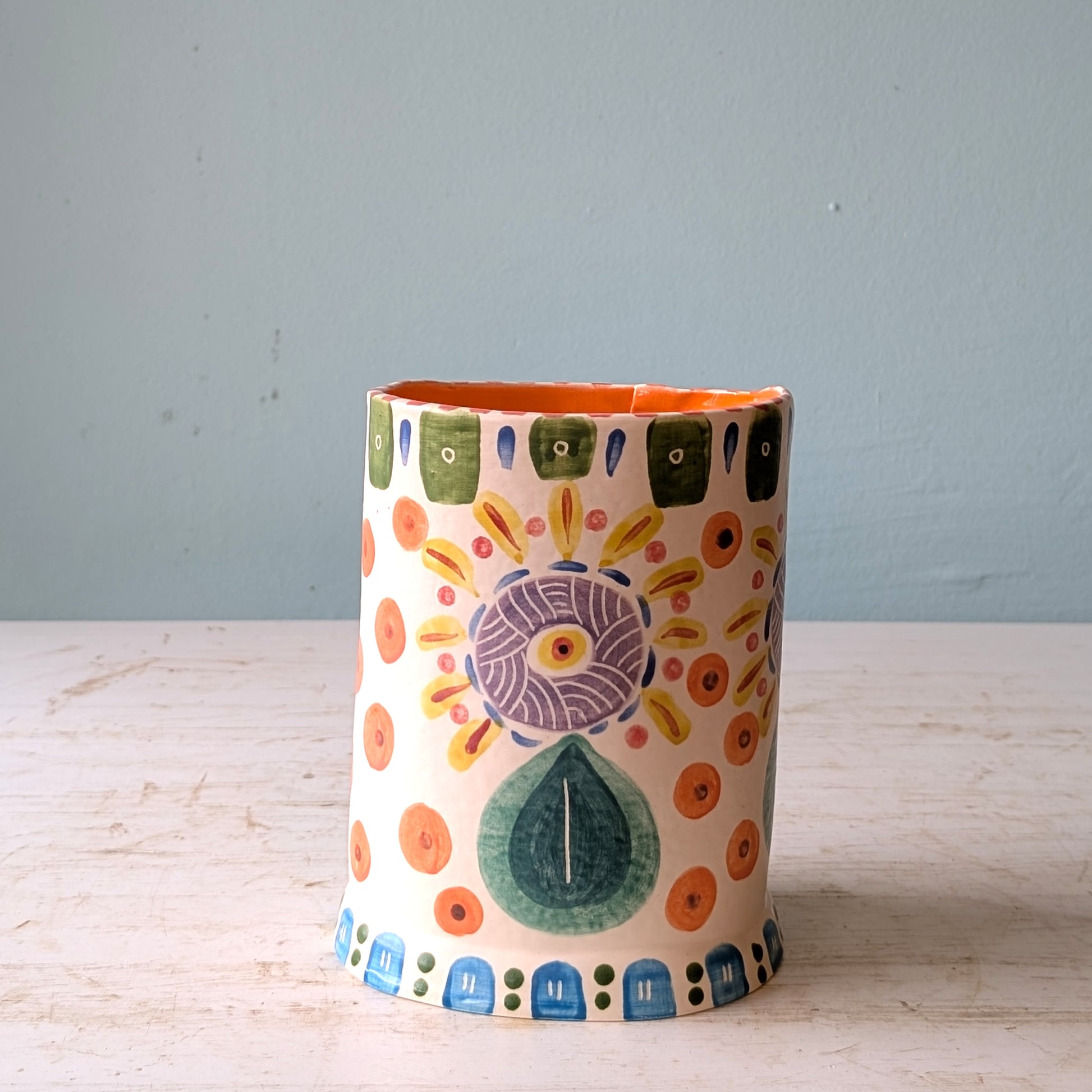 Decorative ceramic vase with colorful patterns on a wooden surface and gray background