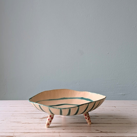 Ceramic bowl with decorative stripes on a wooden surface against a plain wall