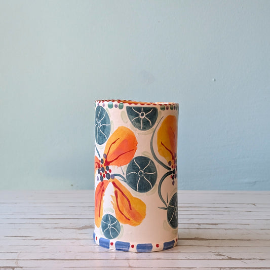 Side view of a white ceramic vase with orange, blue and green floral pattern