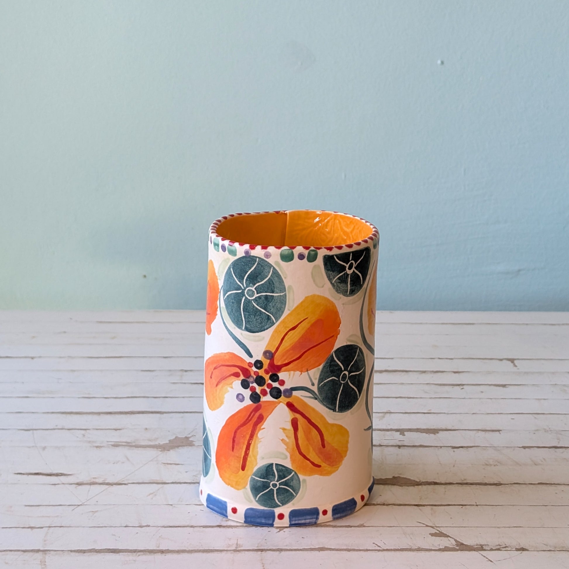 Side and top view of a white ceramic vase with orange, green and blue floral pattern