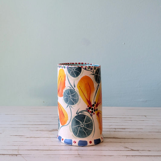 Front view of a white ceramic vase with orange, blue and green floral pattern