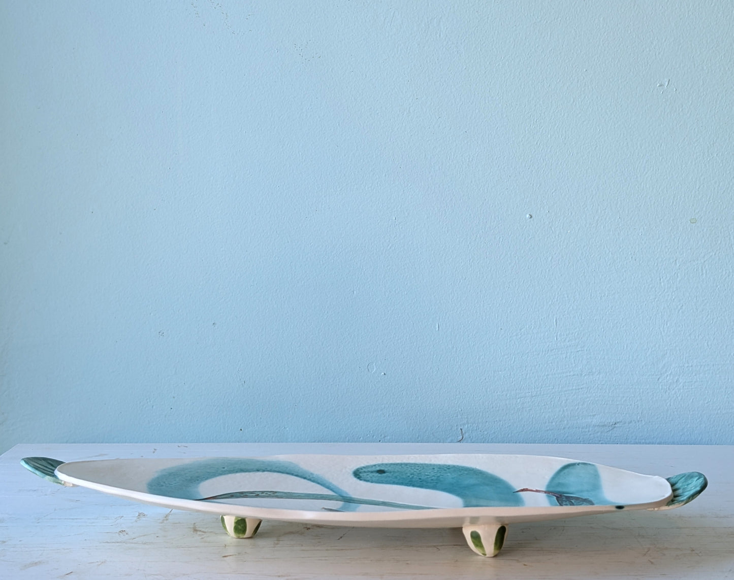 Ceramic platter with leaf design on a light blue background