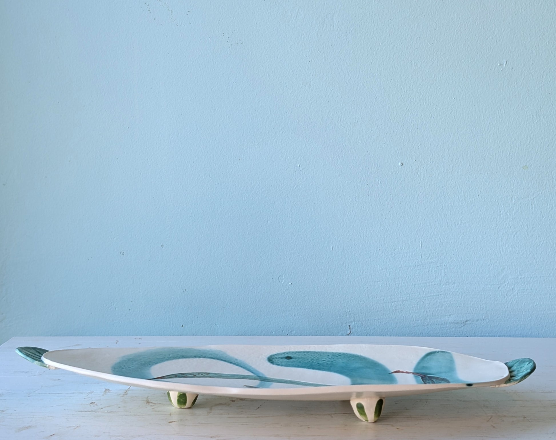 Ceramic platter with leaf design on a light blue background