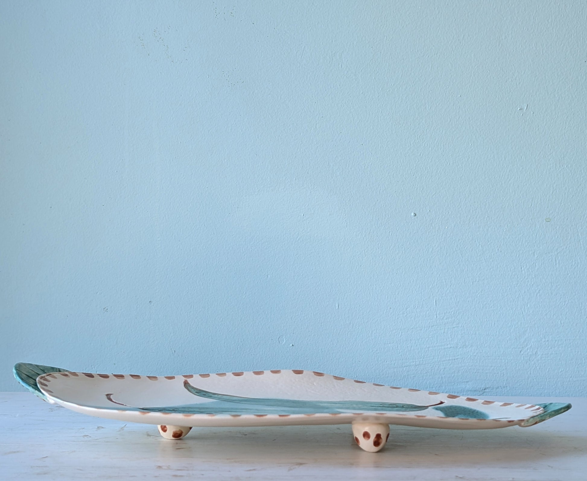 Ceramic platter with decorative design on a light blue background
