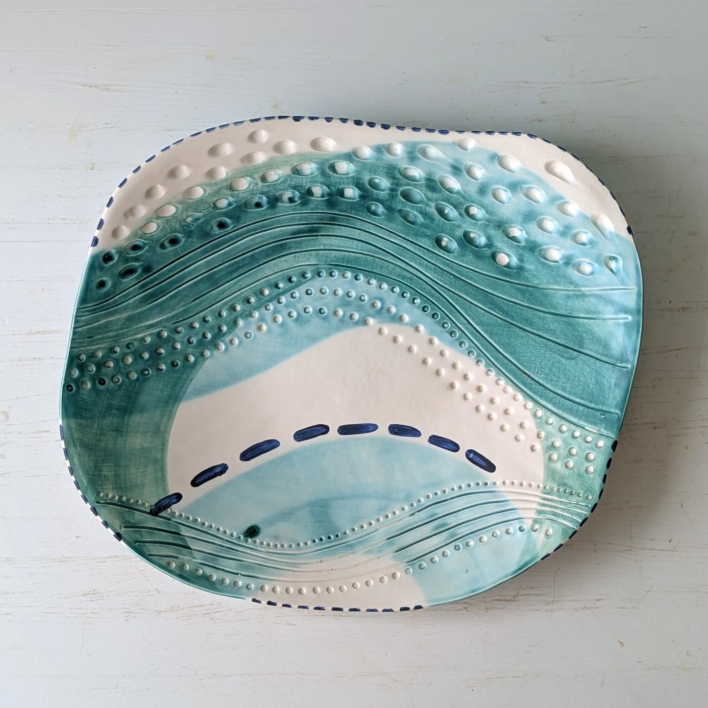 Ceramic platter with wavy blue and white design on a light gray background